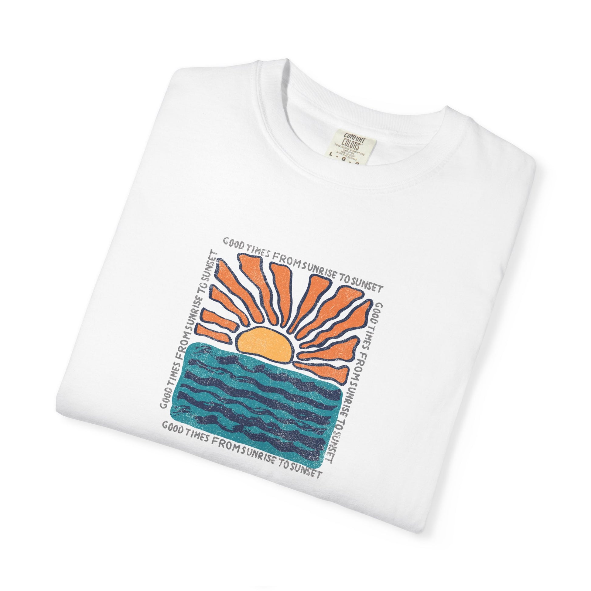 A folded white crewneck t-shirt featuring a colorful graphic print of a rising orange sun over blue wavy water, with the text 'GOOD TIMES FROMSUMBER TO SUNSET' printed around the design.