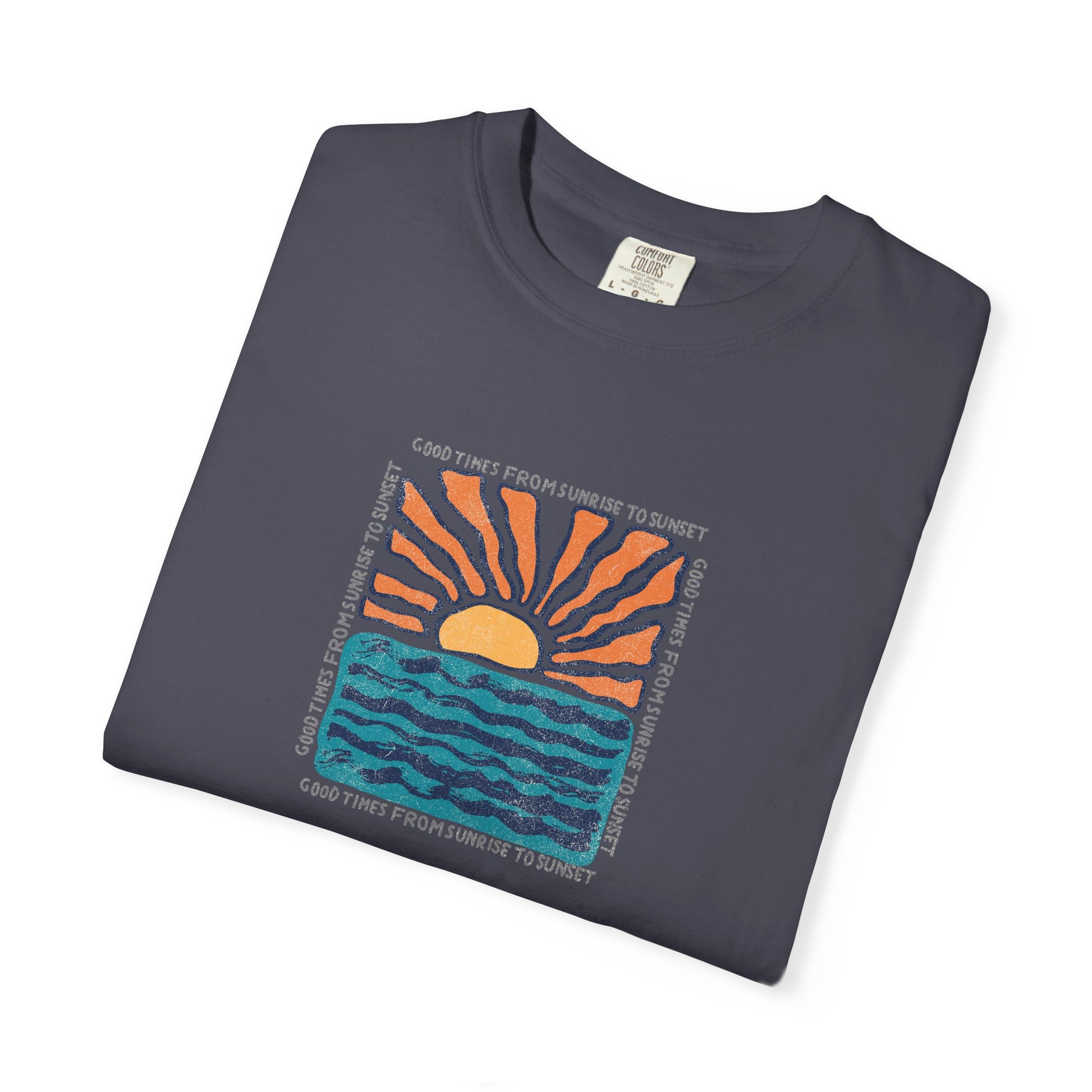 A folded navy blue t-shirt with a colorful graphic of a sunset over wavy blue water, featuring the text 'GOOD TIMES FROM SUNRISE TO SUNSET' printed around the design.