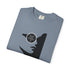 A folded slate blue t-shirt with a black graphic of a woman's profile wearing a circular eyepatch with a pentagram design, shown on a white background.