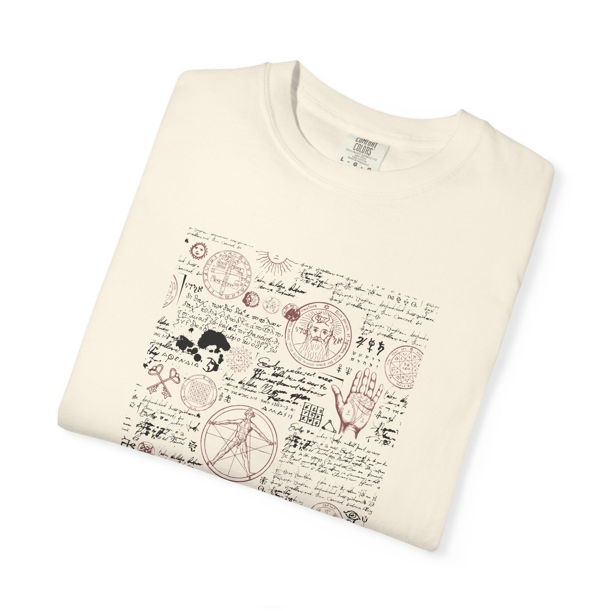 An off-white folded crewneck t-shirt featuring a detailed occult-style graphic print with cursive script, symbols, and illustrations in muted red and brown tones.