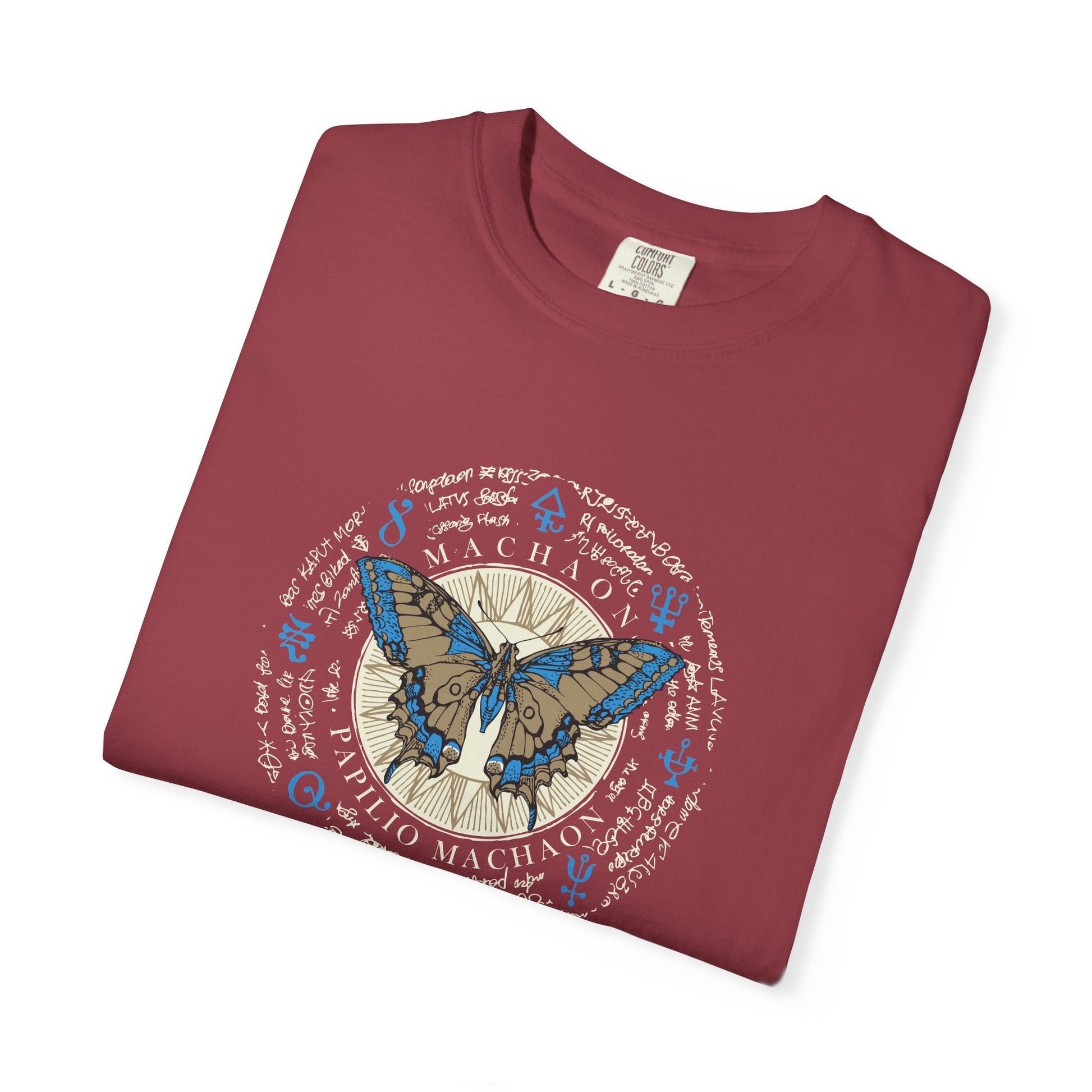 A folded maroon crewneck t-shirt featuring a circular graphic print with a blue and brown butterfly, astrological symbols, and the text 'MACHADO' and 'D. PEDRO MACHADO'.
