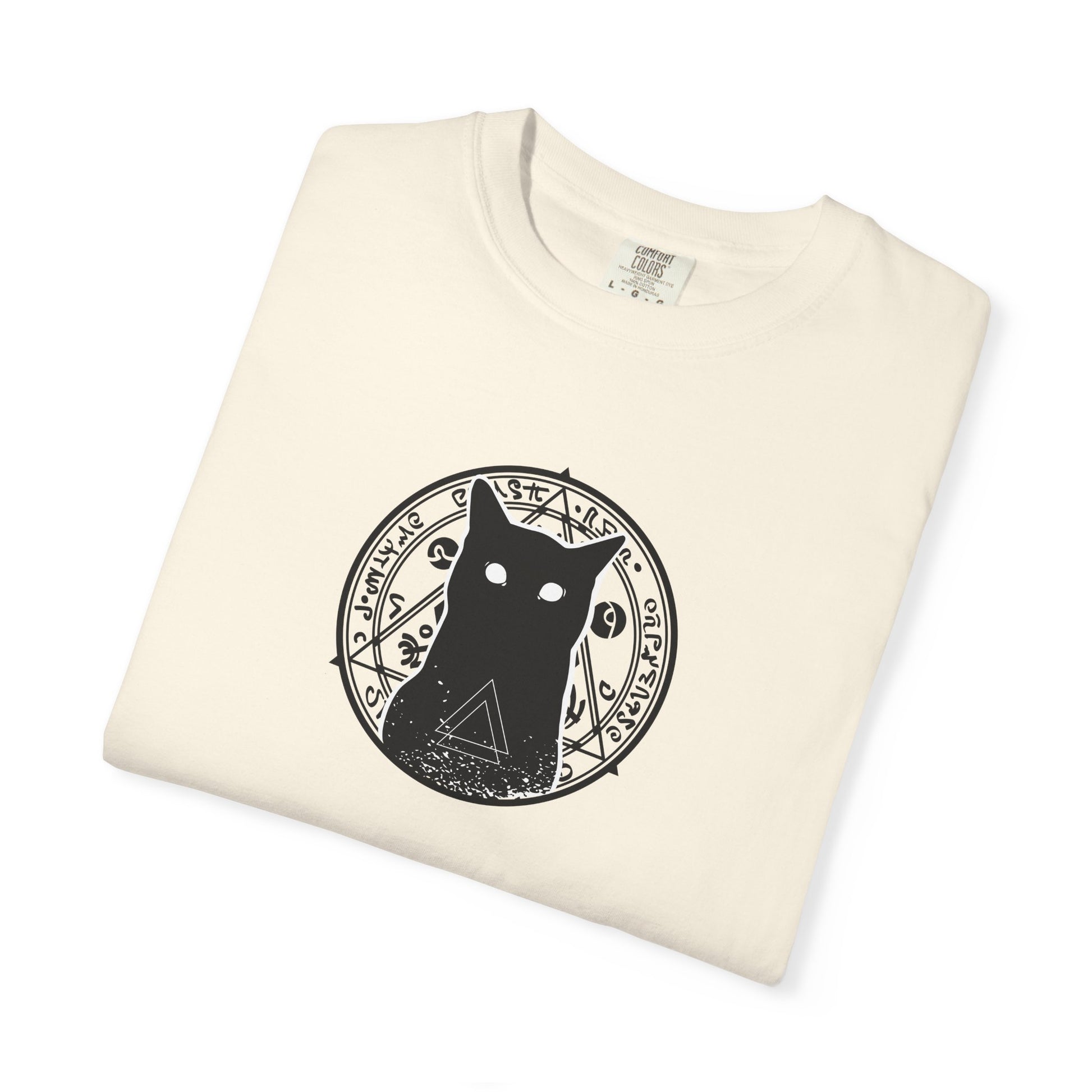 A folded cream-colored t-shirt with a black circular graphic of a cat inside a mystical symbol on the chest, displayed on a clean white background.