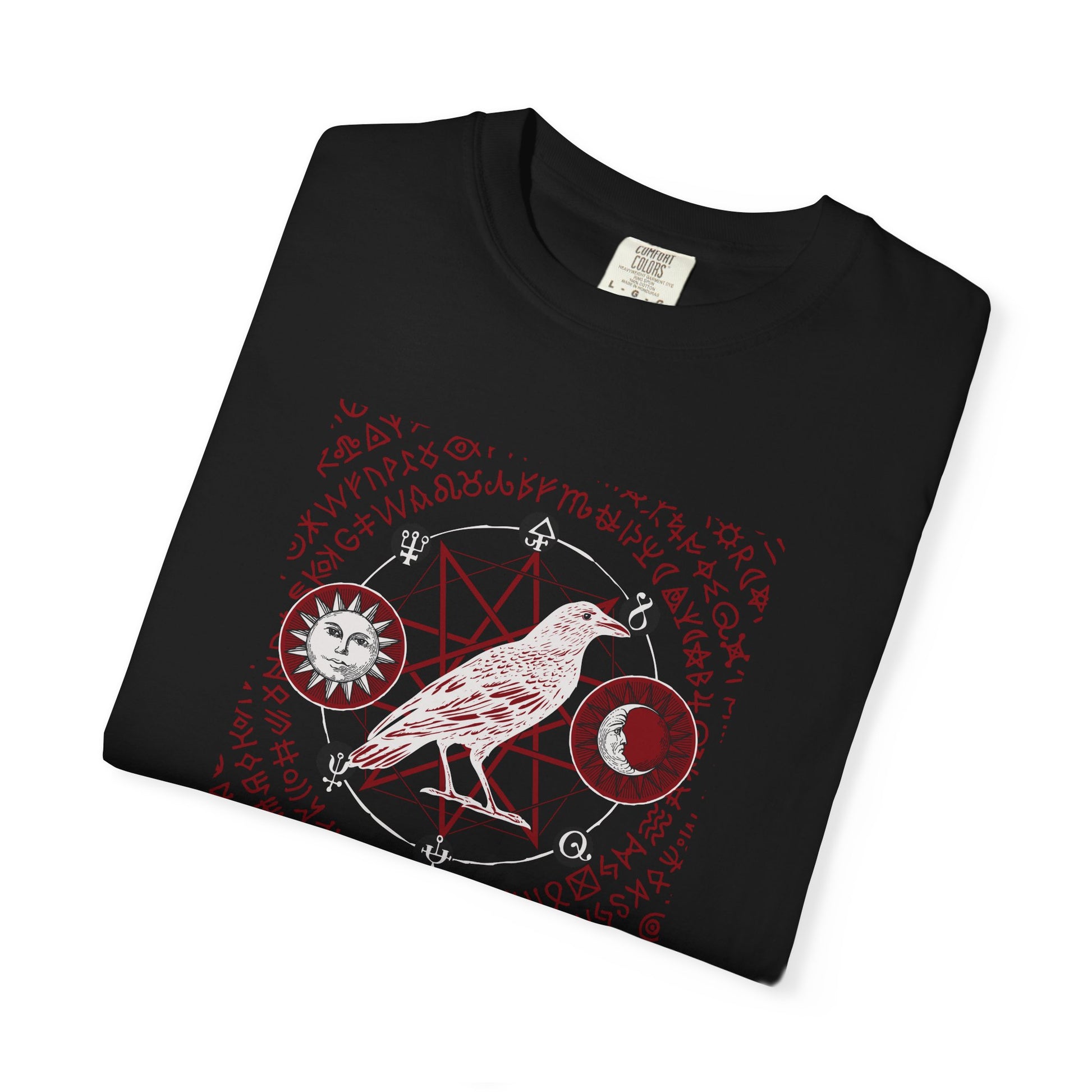 A folded black t-shirt with a red and white occult-style graphic featuring a raven, a pentagram, a sun, and a crescent moon, displayed on a clean white background.