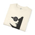 An off-white folded crewneck t-shirt featuring a black graphic print of a stylized face wearing a circular eyepatch with a pentagram design.