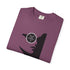 A folded purple crewneck t-shirt with a black graphic of a woman's profile wearing a circular eyepatch with a pentagram design, shown on a white background.