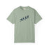 A sage green short-sleeve crewneck t-shirt featuring a dark navy blue graphic of surfers on a beach across the chest, displayed on a clean white background.