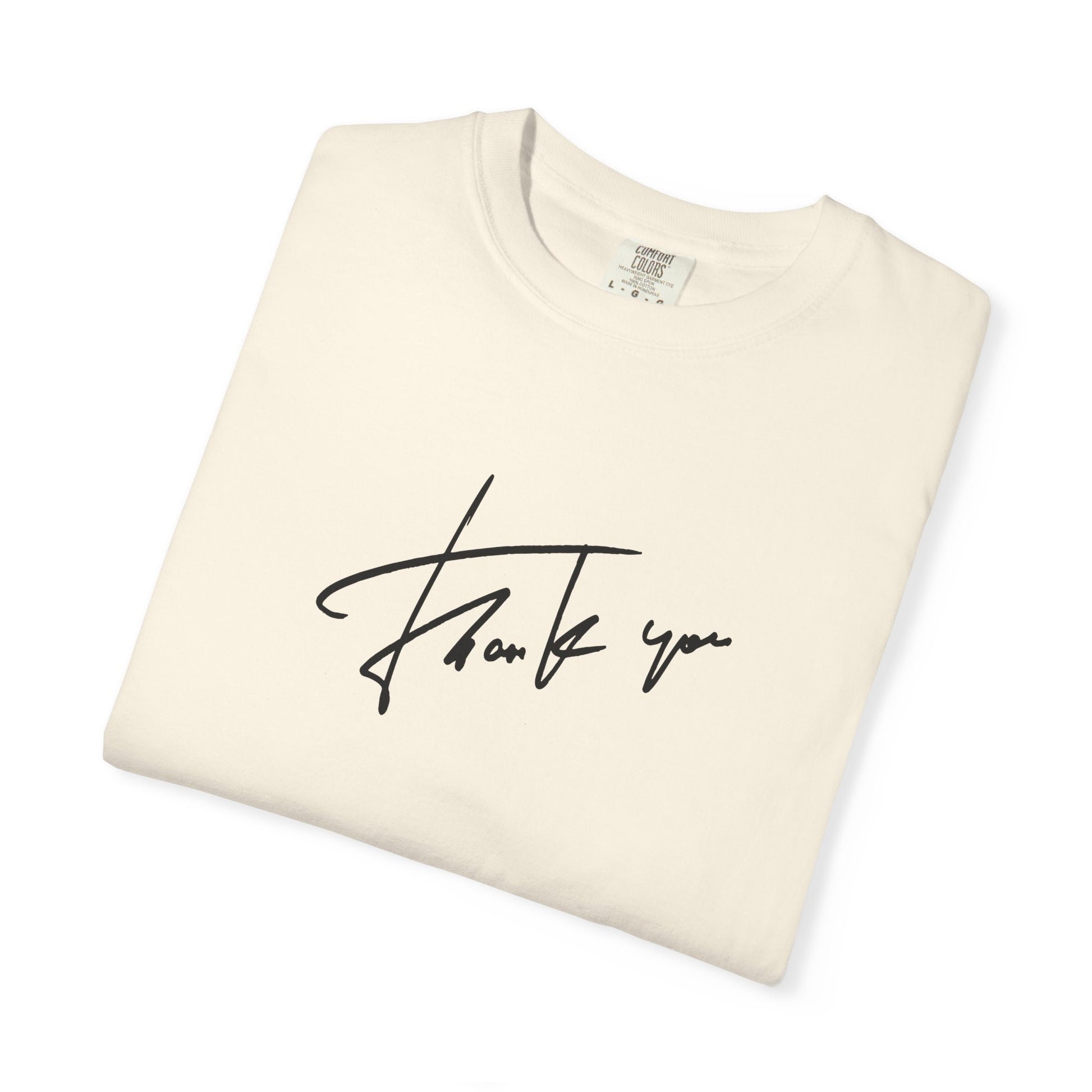 A folded cream-colored t-shirt with a black cursive 'thank you' script printed on the front, displayed on a clean white background.